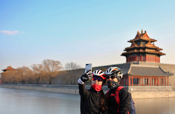 Cyclists stop for a selfie near the Palace Museum on Sunday after a cold front dispersed the weeklong smog in Beijing. (DING SHAN/CHINA DAILY)